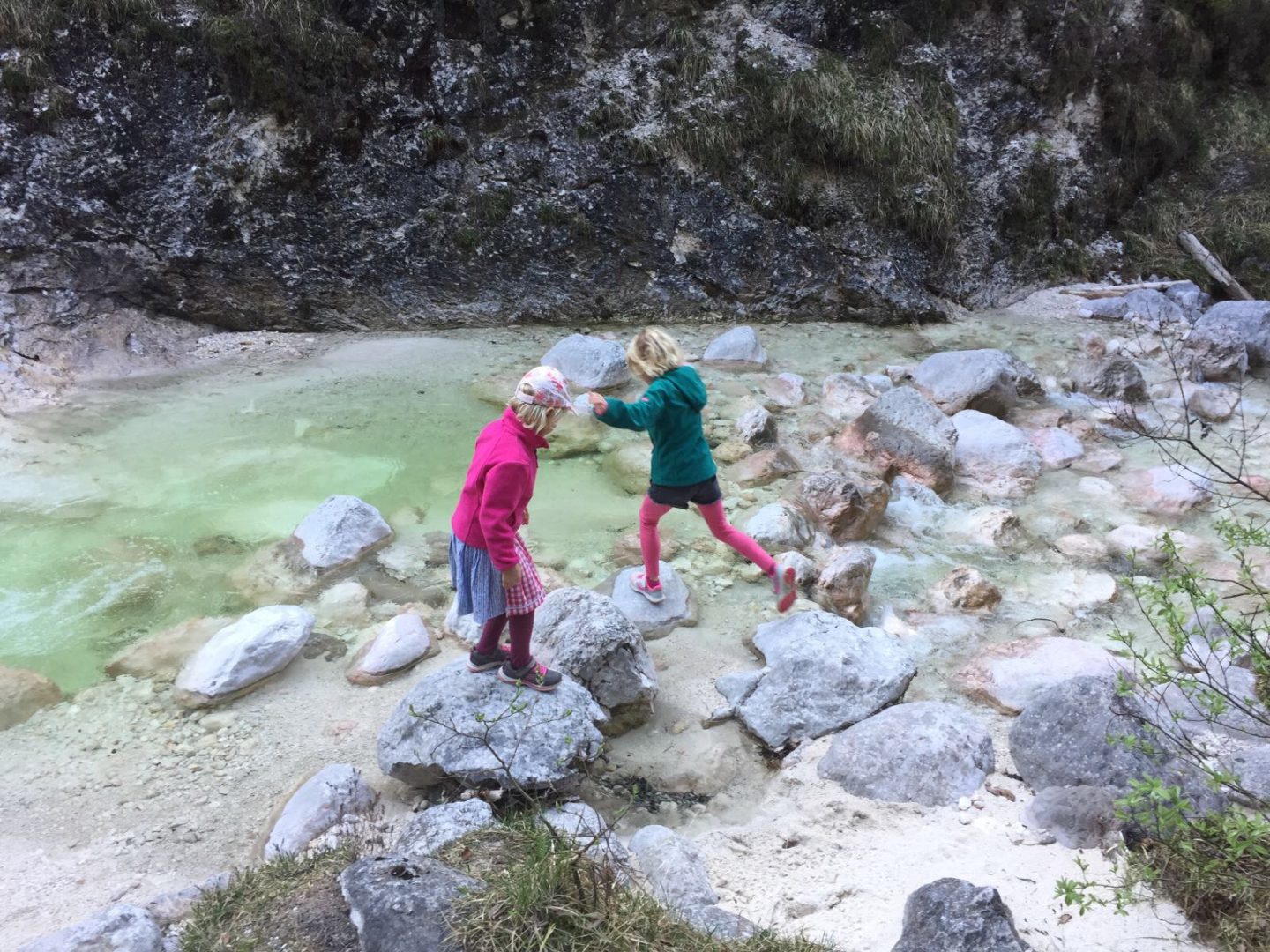 Hüpfen und Balancieren inmitten eines Flusses von Stein zu Stein - zwei Mädels in Action